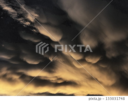 Storm clouds on sunset. Light in the dark and dramatic storm clouds. Background of storm clouds before a thunderstorm. Mammatus clouds 133031748