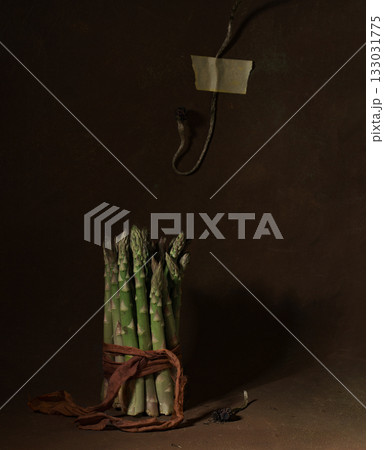 Bundle of lot of whole fresh green asparagus spear tied by green ribbon on brown wood 133031775