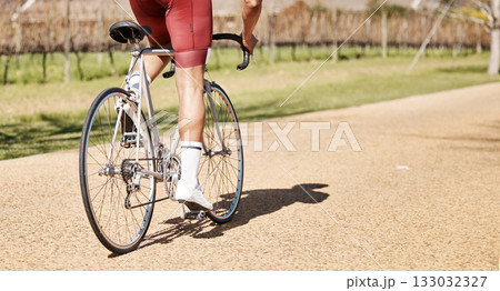 Back of man, bicycle and path in park, exercise and training of triathlon sports in sunshine. Cyclist legs, bike and outdoor cycling trail for freedom, cardio fitness adventure and performance mockup 133032327