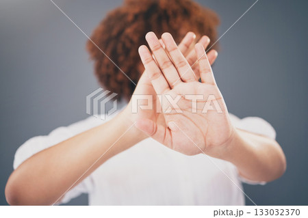 Closeup, hands and woman in studio for stop, warning or domestic violence symbol on grey background. Zoom, justice and hand of girl in protest, caution and protection, scared and abuse awareness 133032370