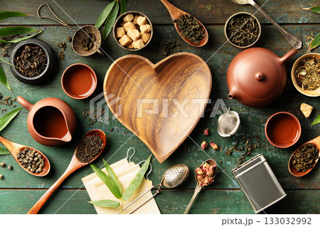 Heart-Shaped Bowl with Teaware and Tea Leaves on Rustic Background Heart-Shaped Bowl with Teaware and Tea Leaves on Rustic Background 133032992
