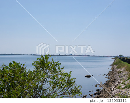 Grado, Italy - July 30th 2024: Dam towards the touristic village of Grado behind the lagoons and islands Grado, Italy - July 30th 2024: Dam towards the touristic village of Grado behind the lagoons and islands 133033311