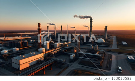 Industrial oil refinery silhouette at sunset with smoke against an orange sky. 133033582