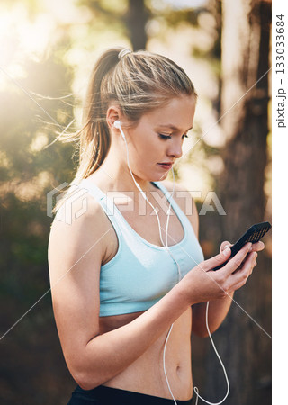 Woman with earphones, phone and fitness with music outdoor, listening for motivation on run in park. Female runner with song choice on mobile, podcast or radio streaming for exercise and health Woman with earphones, phone and fitness with music outdoor, listening for motivation on run in park. Female runner with song choice on mobile, podcast or radio streaming for exercise and health 133033684