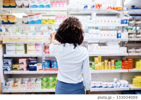 Back, pharmacy and medication with a woman customer buying medicine from a shelf in a dispensary. Healthcare, medical or treatment with a female consumer searching for a health product in a drugstore 133034089