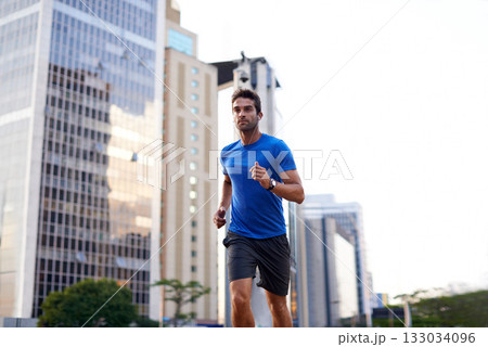 Sports, exercise and man running in the city for health, wellness or training for a marathon. Fitness, runner and male athlete doing an outdoor cardio workout for endurance or speed in an urban town. 133034096