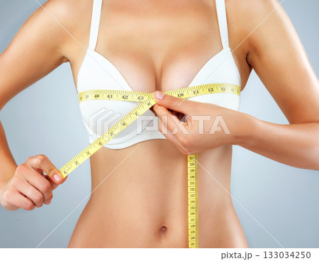 Woman, hands and breast with measuring tape, bust size with body and lose weight isolated on studio background. Female person in underwear, bra and chest measurement, health and diet for weightloss 133034250