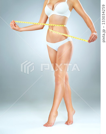 Woman in underwear, body and measuring tape, lose weight and fitness with abdomen isolated on studio background. Female person, waist measurement and diet with health, weightloss and exercise 133034259