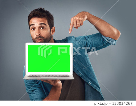 Man, laptop and pointing on mockup green screen for advertising or marketing against a grey studio background. Portrait of male person showing computer display, chromakey or mock up for advertisement Man, laptop and pointing on mockup green screen for advertising or marketing against a grey studio background. Portrait of male person showing computer display, chromakey or mock up for advertisement 133034267