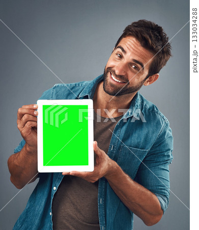 Happy man, portrait and tablet with green screen for advertising, marketing or branding against a grey studio background. Male person showing technology display, chromakey or mock up in advertisement 133034288