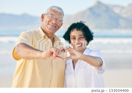 Hands, heart and a senior couple on the beach together during summer for love, romance or weekend getaway. Portrait, travel or emoji with a mature man and woman bonding outdoor on sand by the coast Hands, heart and a senior couple on the beach together during summer for love, romance or weekend getaway. Portrait, travel or emoji with a mature man and woman bonding outdoor on sand by the coast 133034400