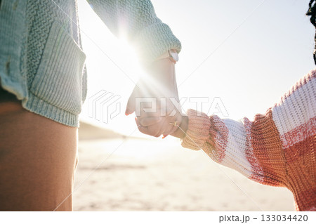 Family, mother and child holding hands at beach, travel and summer with sunshine lens flare and together outdoor. Trust, support with woman and girl on vacation, love and care in nature with closeup Family, mother and child holding hands at beach, travel and summer with sunshine lens flare and together outdoor. Trust, support with woman and girl on vacation, love and care in nature with closeup 133034420