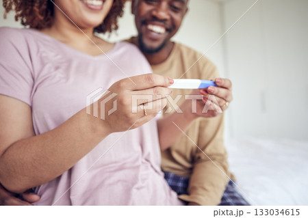 Pregnancy test in hands, happiness with fertility and people having a baby, happy couple with love and care at home. Interracial, black man and pregnant woman, start family with new mother and father 133034615