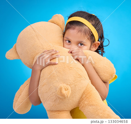 Portrait, hug and child in studio with teddy bear, sweet and innocent on gradient blue background. Face, embracing and child with teddy. hiding and shy, sweet and play while hugging on isolated space 133034658
