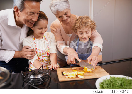 Food, happy children or grandparents teaching cooking skills for a healthy dinner with fruit or vegetables at home. Kids learning, knife or grandmother with old man or diet meal nutrition in kitchen Food, happy children or grandparents teaching cooking skills for a healthy dinner with fruit or vegetables at home. Kids learning, knife or grandmother with old man or diet meal nutrition in kitchen 133034847