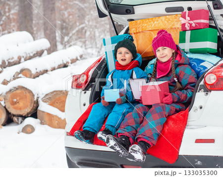Merry Christmas concept. Two children in colorful winter suits open Christmas presents 133035300
