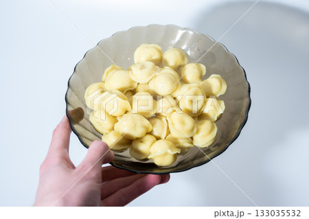 Hand Holding Bowl of Boiled Dumplings on Light 133035532