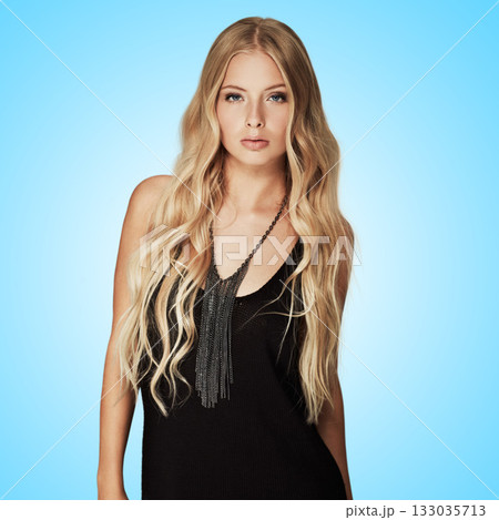 Beauty, fashion and portrait of a woman in studio with makeup, cosmetics and hair extensions. Female aesthetic model with a natural glow, luxury skincare and seductive pose on a blue background 133035713