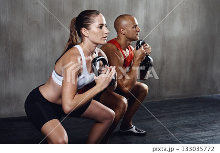 Fitness, people and workout with kettlebell in squat for weightlifting or exercise together at gym. Serious man and woman lifting weight for strong exercising, power or glutes in training indoors 133035772