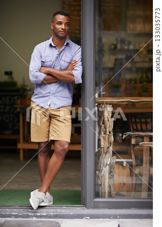 Coffee shop, arms crossed and man as small business owner at door thinking of future ideas. African entrepreneur, manager or restaurant waiter with smile for service, career pride and confidence Coffee shop, arms crossed and man as small business owner at door thinking of future ideas. African entrepreneur, manager or restaurant waiter with smile for service, career pride and confidence 133035773