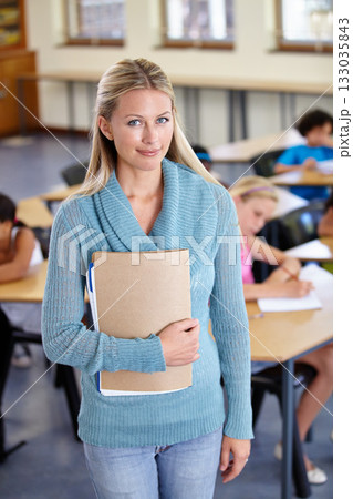 Teacher, portrait and woman with binder in class, elementary school or classroom. Education, teaching and female educator with folder, paperwork or documents for serious learning, knowledge or study. 133035843