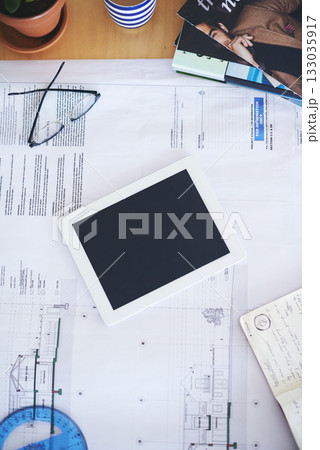 Tablet, blueprint and mockup on office desk above for architecture planning, strategy or layout. Top view of building paperwork, floor plan or architect notes in construction with tech screen display Tablet, blueprint and mockup on office desk above for architecture planning, strategy or layout. Top view of building paperwork, floor plan or architect notes in construction with tech screen display 133035917