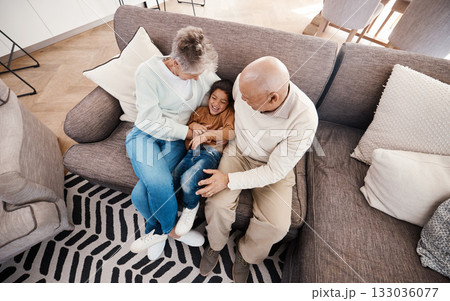 Relax, playful and child with grandparents on sofa of living room for bonding, affectionate and embrace. Support, care and break with senior people and boy at home for happiness, generations and hug 133036077
