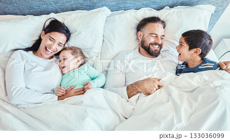 Waking up, bed and family relax, happy and bond while resting, talking and laughing from above at home. Bedroom, fun and kids with parents in the morning, playful and caring while lying and embracing 133036099