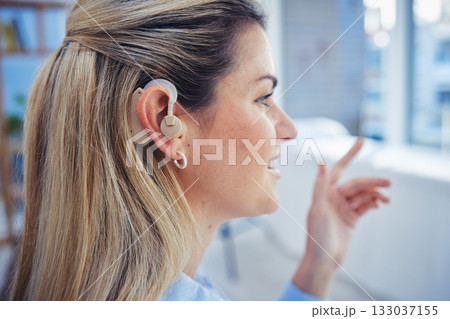 Deaf, hearing aid and disability with a business woman at work in her office for productivity. Healthcare, senses and listening with a young female employee hearing information while working indoor 133037155