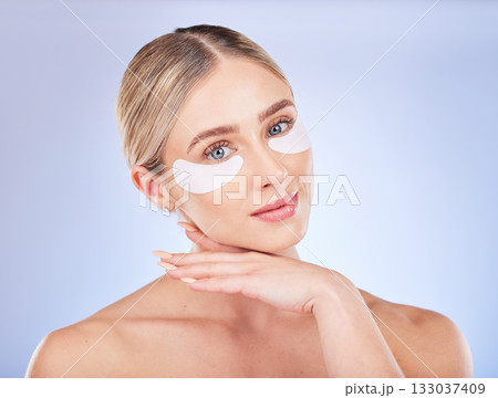 Face, skincare and woman with eye patches in studio isolated on a blue background. Dermatology portrait, cosmetics and beauty of female model with facial mask for healthy skin, anti aging or collagen Face, skincare and woman with eye patches in studio isolated on a blue background. Dermatology portrait, cosmetics and beauty of female model with facial mask for healthy skin, anti aging or collagen 133037409