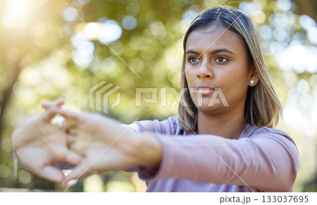 Fitness, nature and woman doing a stretching exercise before a workout in the park or garden. Sports, wellness and female athlete doing a arm warm up workout before pilates training outdoor in field. 133037695