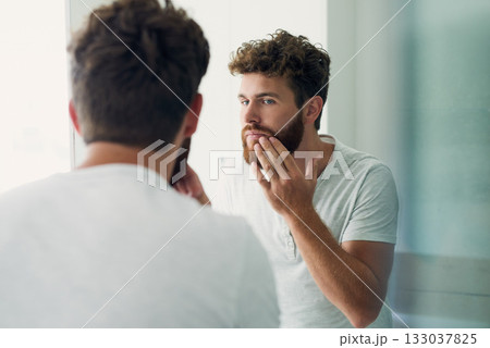 Skincare, beauty and beard with a man in the bathroom of his home in the morning for fresh hygiene. Mirror, reflection and self care with a handsome young male person checking his face or skin 133037825