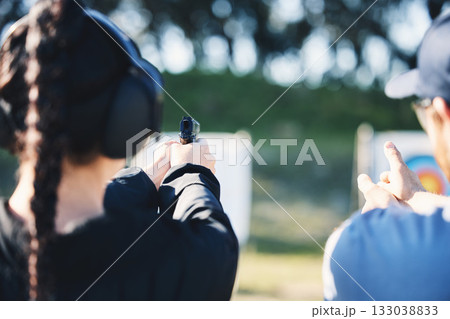 Woman, gun and learning to shoot outdoor with instructor at shooting range for target training. Safety and security with hand teaching person sport game or aim with gear and firearm for focus Woman, gun and learning to shoot outdoor with instructor at shooting range for target training. Safety and security with hand teaching person sport game or aim with gear and firearm for focus 133038833