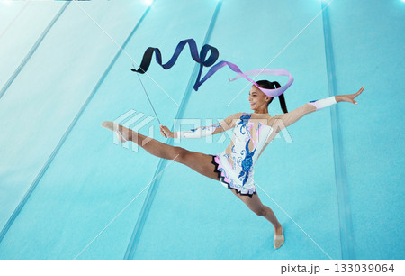 Gymnastics, woman with ribbon for dance and sport performance, flexibility with professional athlete in gym and top view. Rhythmic gymnast, leg in air with fitness, grace and action with dancing Gymnastics, woman with ribbon for dance and sport performance, flexibility with professional athlete in gym and top view. Rhythmic gymnast, leg in air with fitness, grace and action with dancing 133039064