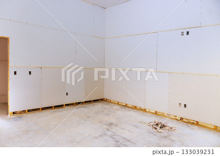 Construction site with unfinished drywall installation in bare room during renovation process Construction site with unfinished drywall installation in bare room during renovation process 133039231