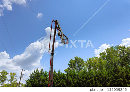 Construction crew using lift to work on tall structure under blue sky with clouds 133039246