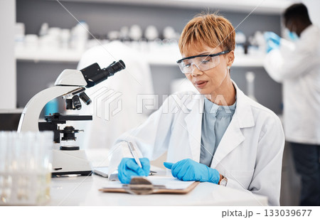 Scientist, woman and writing lab report with results, focus or analysis for pharma development. Science expert, checklist and documents with microscope, innovation and results of pharmaceutical trial 133039677