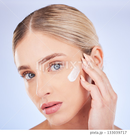 Skincare, face portrait and woman with cream in studio isolated on a blue background. Dermatology closeup, beauty cosmetics and young female model apply hydration lotion, creme or moisturizer product Skincare, face portrait and woman with cream in studio isolated on a blue background. Dermatology closeup, beauty cosmetics and young female model apply hydration lotion, creme or moisturizer product 133039717
