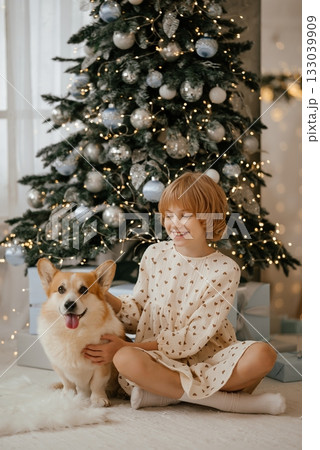 Child with Dog by Christmas Tree Smiling Joyfully 133039909
