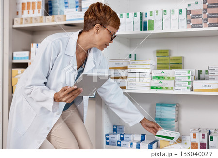 Pharmacist woman, tablet and medicine shelf to check inventory and product information search. Person with pharmacy app in clinic or shop for pharmaceutical, medical and health care consultation 133040027