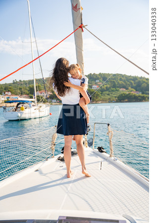 Mother and daughter spending time together on the bow of a sailing yacht. Family bonding, sea adventure, and peaceful travel lifestyle Mother and daughter spending time together on the bow of a sailing yacht. Family bonding, sea adventure, and peaceful travel lifestyle 133040338
