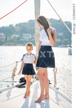 Mother and daughter spending time together on the bow of a sailing yacht. Family bonding, sea adventure, and peaceful travel lifestyle Mother and daughter spending time together on the bow of a sailing yacht. Family bonding, sea adventure, and peaceful travel lifestyle 133040357