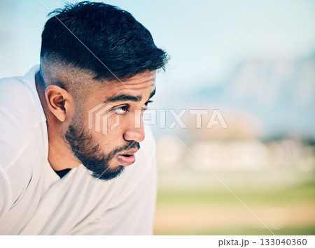 Tired, breathing and sports man at a field for training, break and breathing exercise on blurred background. Athletic, sports and indian guy stop to breathe after exercise, workout or match practice 133040360