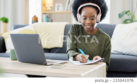 Woman, student writing and headphones for home education, e learning and studying on her laptop. African person with notes, phd research proposal and planning goals on computer and listening to music Woman, student writing and headphones for home education, e learning and studying on her laptop. African person with notes, phd research proposal and planning goals on computer and listening to music 133041076