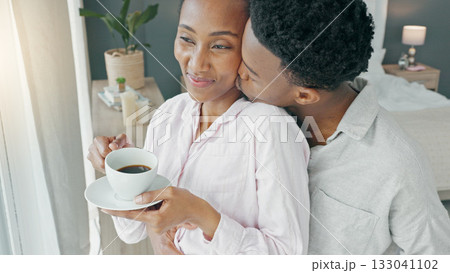 Couple, kiss and coffee in the morning for love, happiness and care, watch and view from window in bedroom of home. .Romance, black woman and man in room embrace for commitment and healthy marriage Couple, kiss and coffee in the morning for love, happiness and care, watch and view from window in bedroom of home. .Romance, black woman and man in room embrace for commitment and healthy marriage 133041102