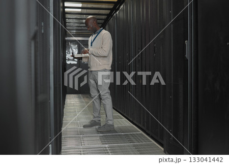 Server room, data center or IT black man with laptop for research, engineer working in dark server room. Computer, cybersecurity and analytics with male programmer problem solving or troubleshooting Server room, data center or IT black man with laptop for research, engineer working in dark server room. Computer, cybersecurity and analytics with male programmer problem solving or troubleshooting 133041442