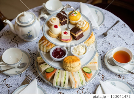 Traditional English afternoon tea with a tiered stand of sandwiches scones pastries and tea 133041472