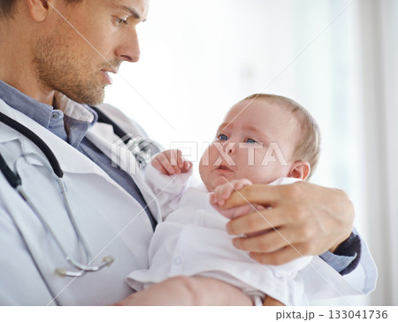 Doctor, sick and sad baby in clinic for healthcare assessment, pediatrics support and help. Pediatrician holding unhappy newborn kid for hospital service, medical test and wellness of crying children 133041736