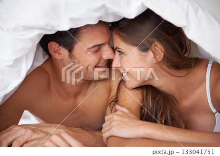 Happy, love and couple in bed, waking up and bonding in a bedroom together, flirting and romantic. Romance, man and woman relax, intimate and resting at house for valentines day, anniversary or bond 133041751