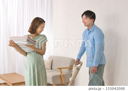 妊婦の女性と楽しそうに話しながら掃除機をかける若い男性 133042098